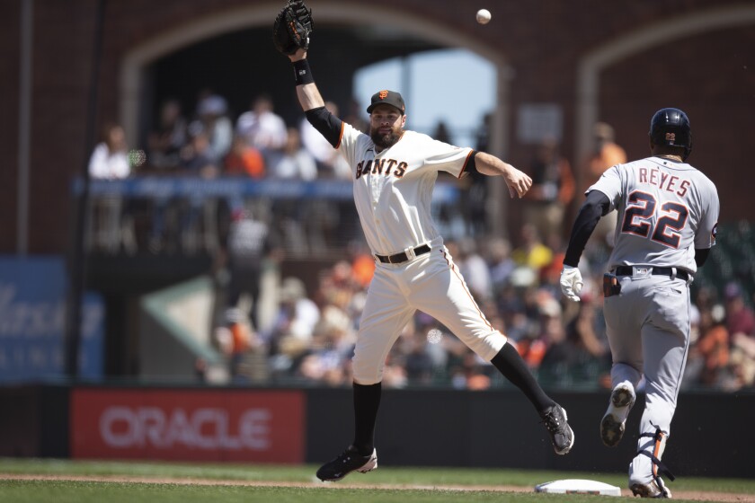 San Francisco Giants first baseman Brandon Belt (9) cannot get a glove on an errant throw that allowed Detroit Tigers' Victor Reyes (22) to reach first during the seventh inning of a baseball game Wednesday, June 29, 2022, in San Francisco. Reyes was credited with a single, and advanced to second on the throwing error. (AP Photo/D. Ross Cameron)