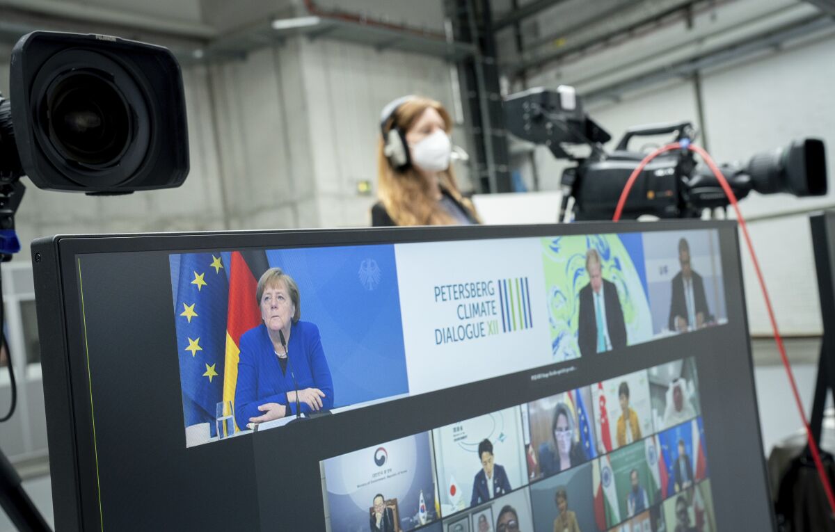 German Chancellor Angela Merkel (CDU) participates in the digital Petersberg Climate Dialogue, seen on the top left of a monitor, in Berlin, Germany, Thursday, May 6, 2021. (Kay Nietfeld/dpa via AP)