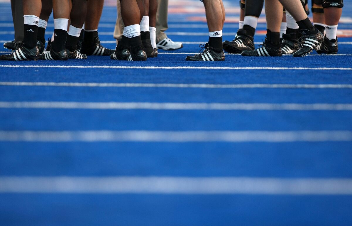 A view of players' cleats on Boise State's blue turf. Boise State and the Mountain West have been fighting over whether the school should continue to receive a bonus from the conference's future TV contracts.