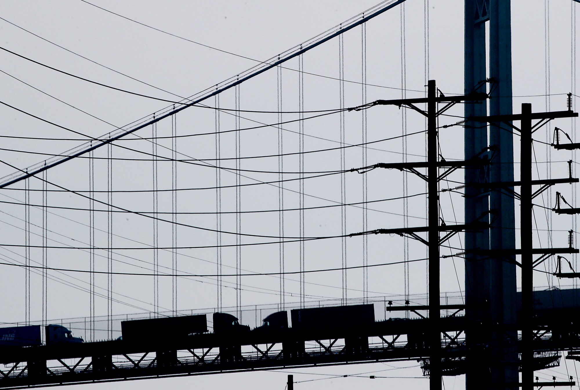 Trucks haul cargo containers across the Vincent Tomas Bridge
