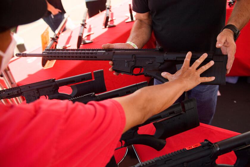 A clerk shows a customer a TPM Arms LLC California-legal featureless AR-10 style .308 rifle displayed for sale at the company's booth at the Crossroads of the West Gun Show at the Orange County Fairgrounds on June 5, 2021 in Costa Mesa, California. - Gun sales increased in the US following Covid-19 pandemic lockdowns. On June 4, a San Diego federal court judge overturned California's three-decade old ban on assault weapons, defined as a semiautomatic rifle or pistol with a detachable magazine and certain features, but granted a 30-day stay for a State appeal and likely future court decisions on the constitutionality of the ban under the Second Amendment. An industry of California legal "featureless" or "compliant" AR-15 style rifles developed for California consumers, adapting to the law with design changes to the popular rifle. (Photo by Patrick T. FALLON / AFP) (Photo by PATRICK T. FALLON/AFP via Getty Images)