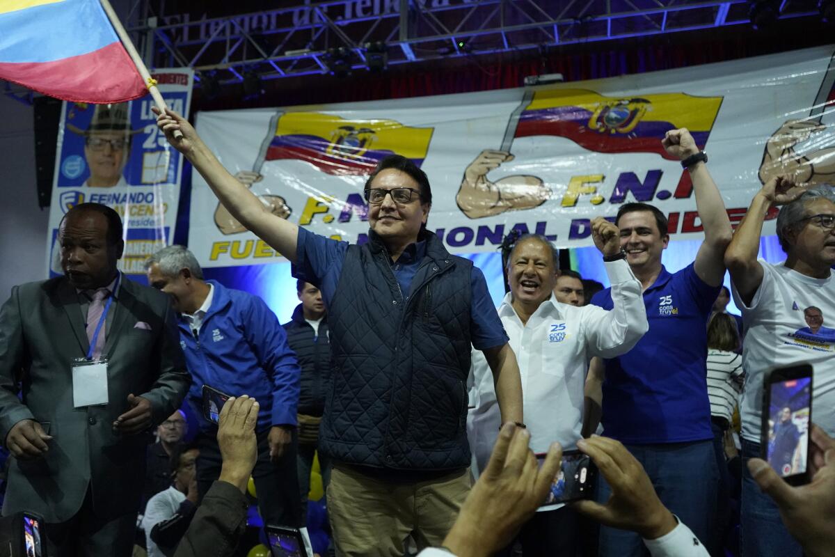 A political candidate surrounded by supporters waves the Ecuadorean flag 