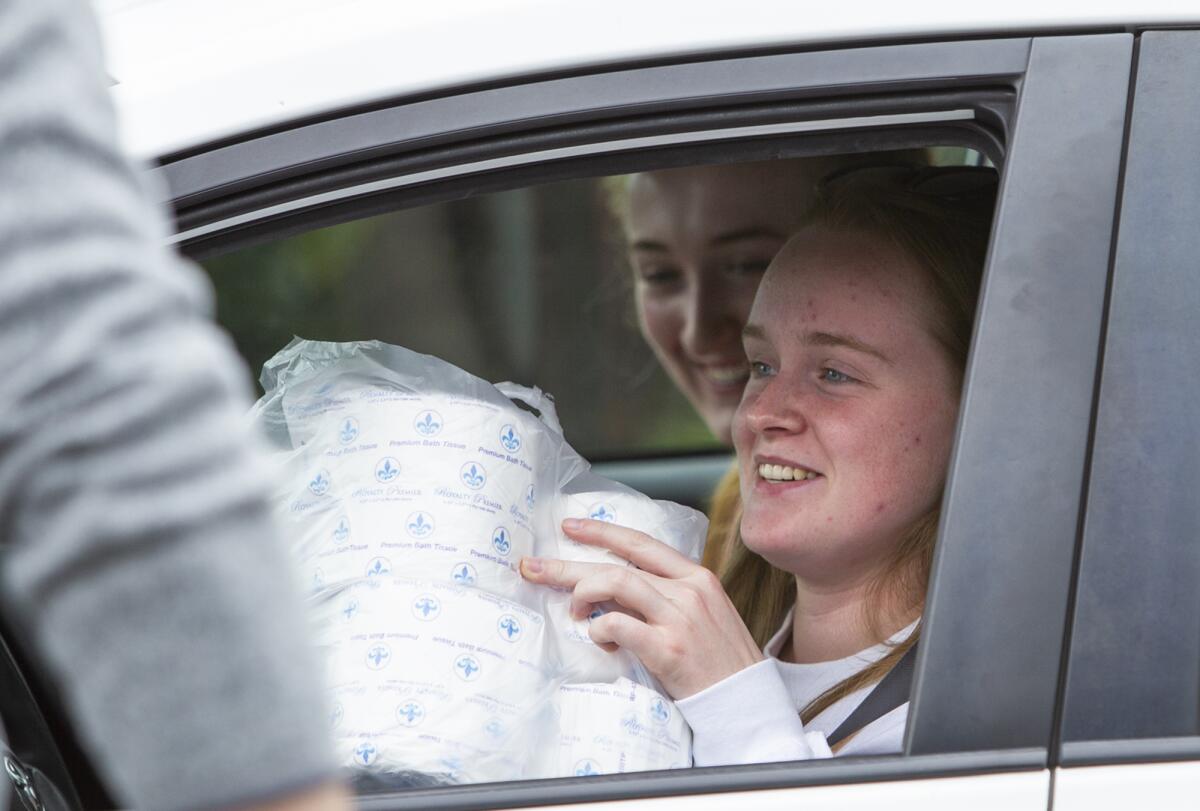A driver gets a bundle of 10 rolls of toilet paper in the parking lot of Malarky's Irish Pub in Newport Beach on Friday.