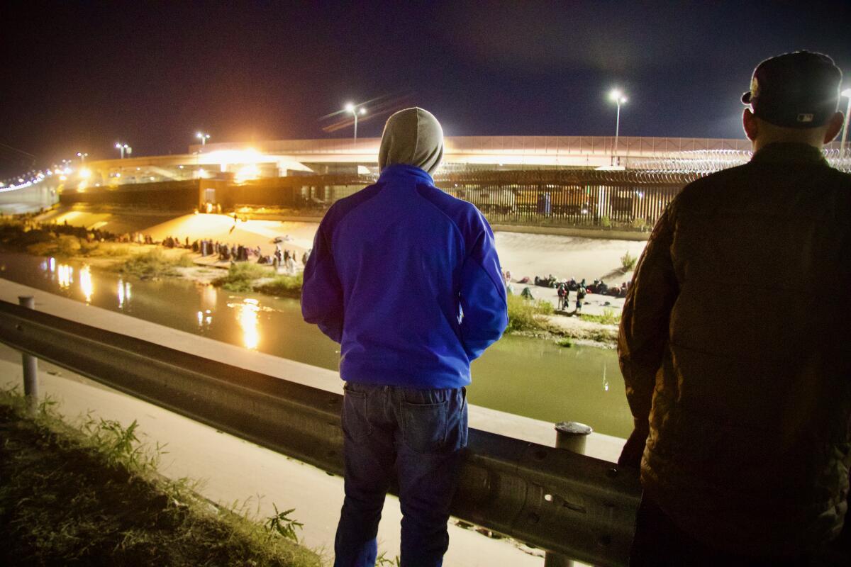 Dos migrantes venezolanos en Ciudad Juárez miran hacia el muro fronterizo 