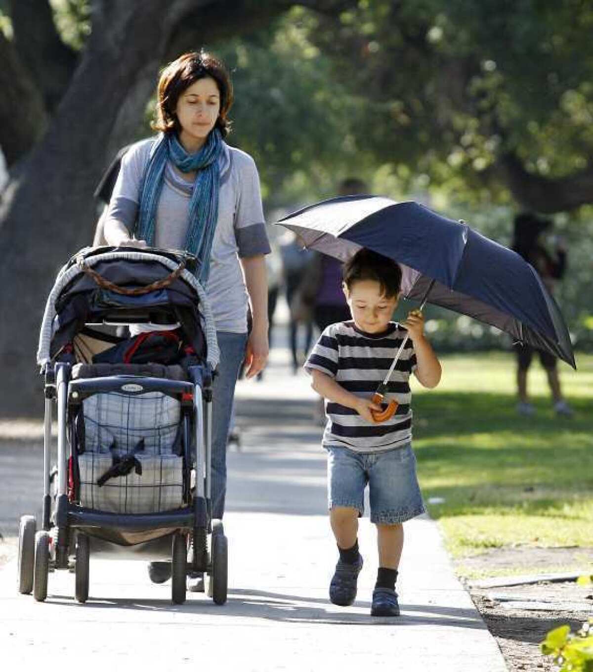 Edgar Galstyan, 3, holds an umbrella, partly to keep from the sun, but more for play, as he walks home with his mom Lusine Tsaturyan after making the morning drop off of a sibling at R.D. White Elementary School in Glendale.