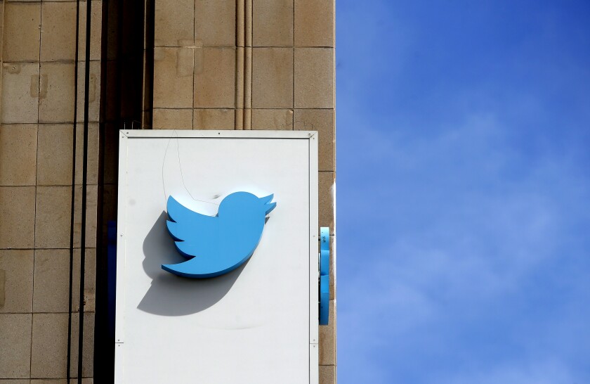 The Twitter bird symbol hangs on the side of a building