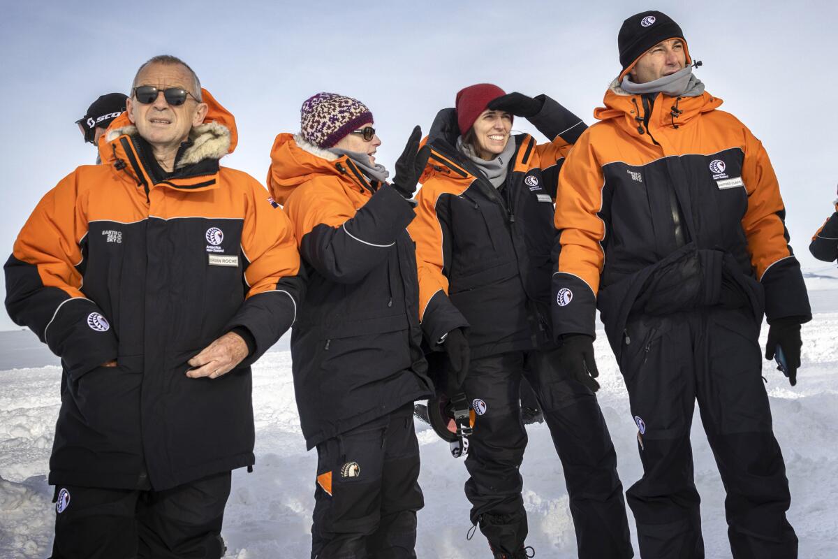 Four people standing, in cold-weather gear looking around Antarctica.