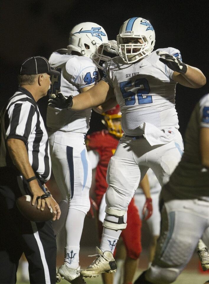Corona del Mar High's Bryan Samudro (52) jumps up to celebrate a touchdown by teammate Jaydin Moses, left, during the first half against Woodbridge.