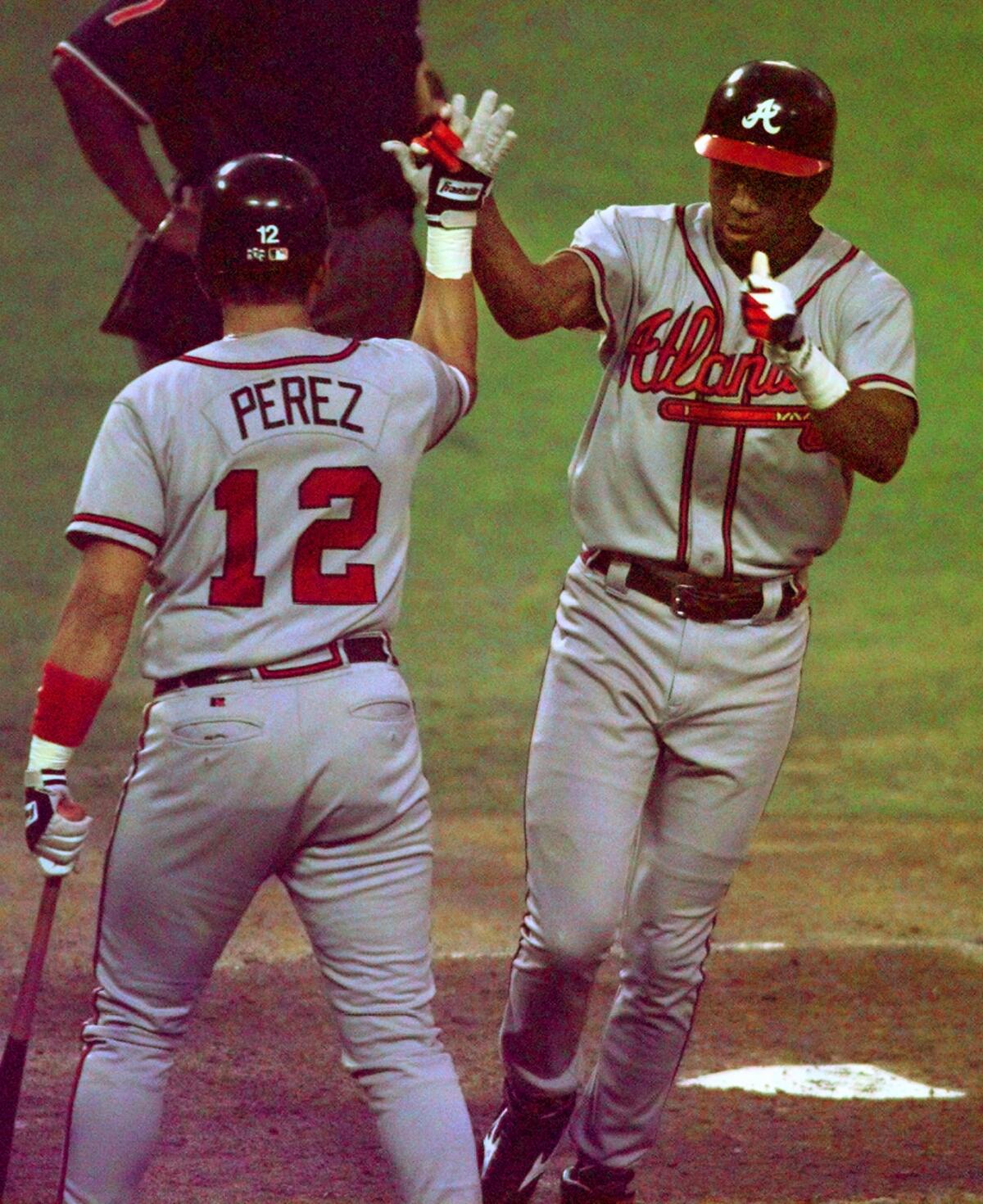 Atlanta's Jermaine Dye, right, high–fives teammate Eddie Perez after hitting a home run