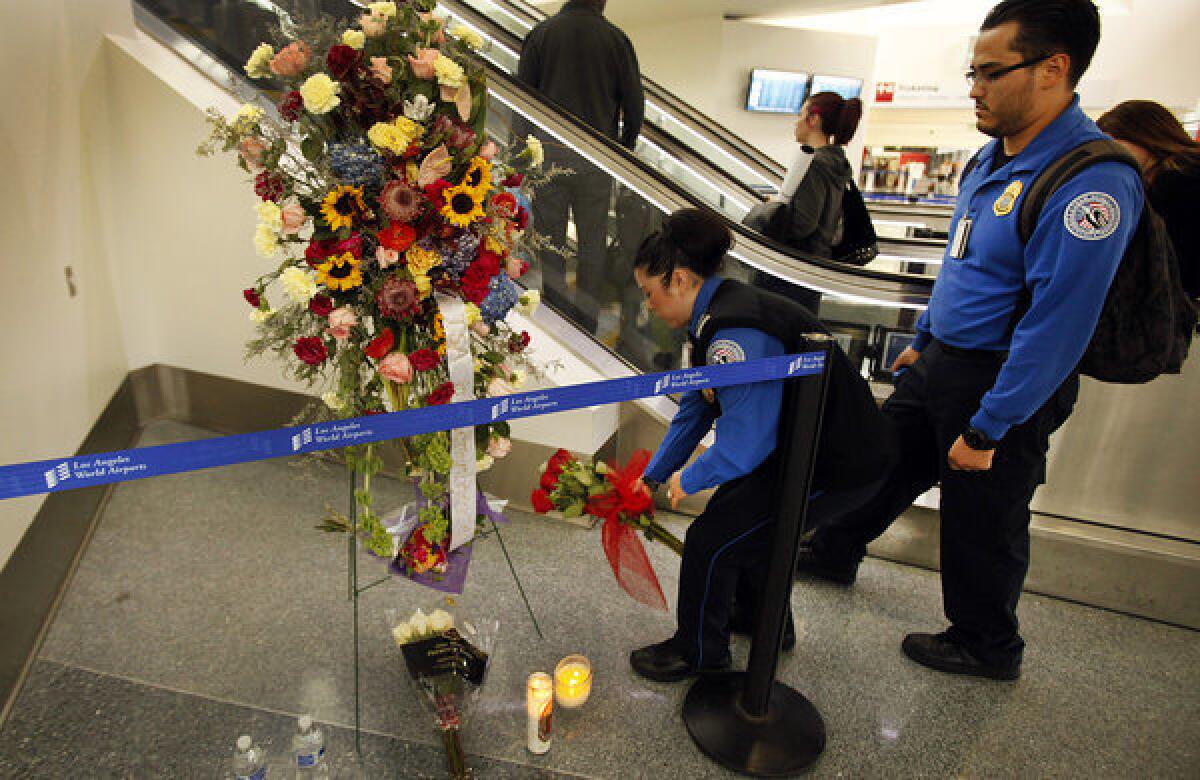 Transportation Security Administration agents leave flowers and say a prayer at a memorial at LAX.
