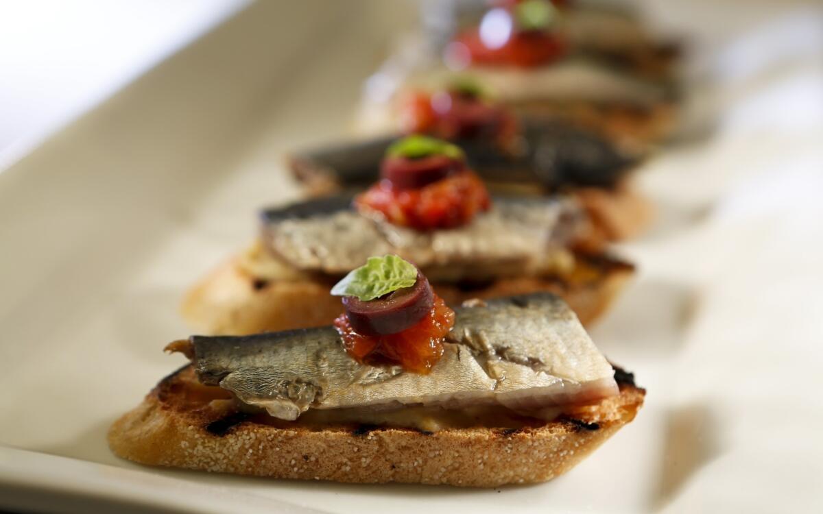 Pickled sardines on toast with artichoke puree, tomato and black olive