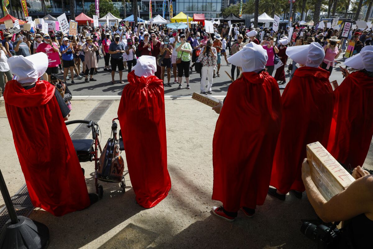 Marchers dressed in costumes referencing TV series "The Handmaid's Tale" 