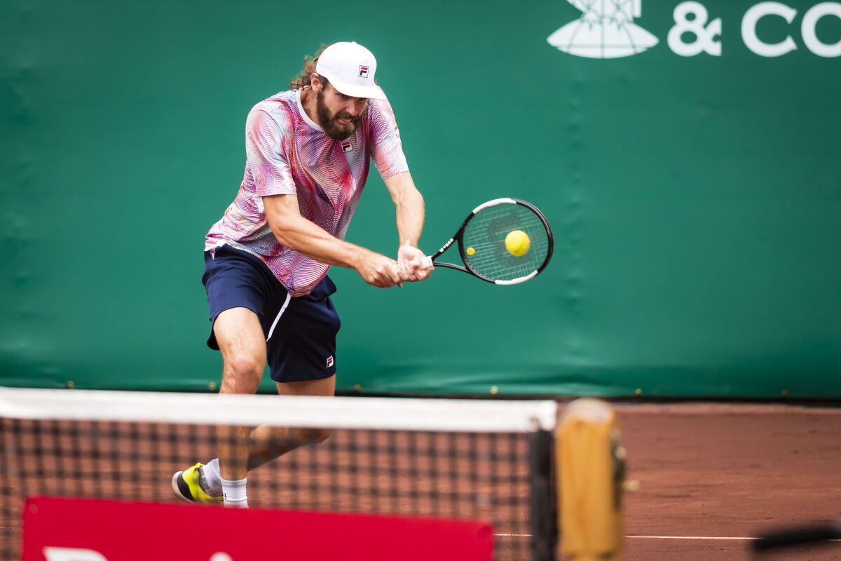Reilly Opelka, of the United States, hits a backhand shot to John Isner, of the United States, in the men's singles final at the U.S. Clay Court Tennis Championships at River Oaks Country Club, Sunday, Apr 10, 2022, in Houston. (Joe Buvid/Houston Chronicle via AP)