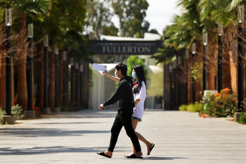 FULLERTON-CA-APRIL 21, 2020: Cal State University Fullerton student Linh Trinh, 21, right, and her boyfriend Tan Nguyen, 21, walk around a deserted CSUF campus on Tuesday, April 21, 2020. The school is planning to begin Fall semester with online classes, one of the first universities in the nation to make that move as campuses throughout the country grapple with how long to stay closed to most students amid the coronavirus pandemic. (Christina House / Los Angeles Times)