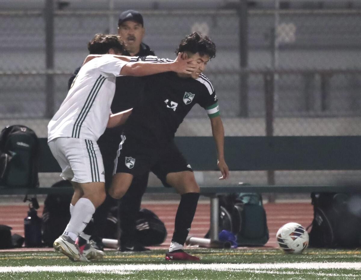 Costa Mesa's Gabriel Garcia (13) takes a hand to the face as he battles for a loose ball with Saddleback's Andy Carbajal.
