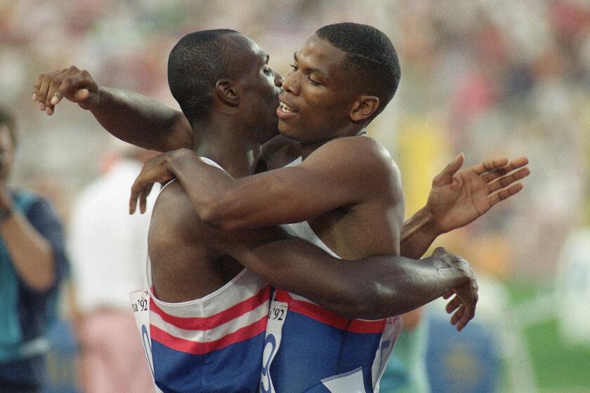 USA teammates Quincy Watts of Detroit, Mich., right and Steve Lewis of Fremont, Calif. hug.