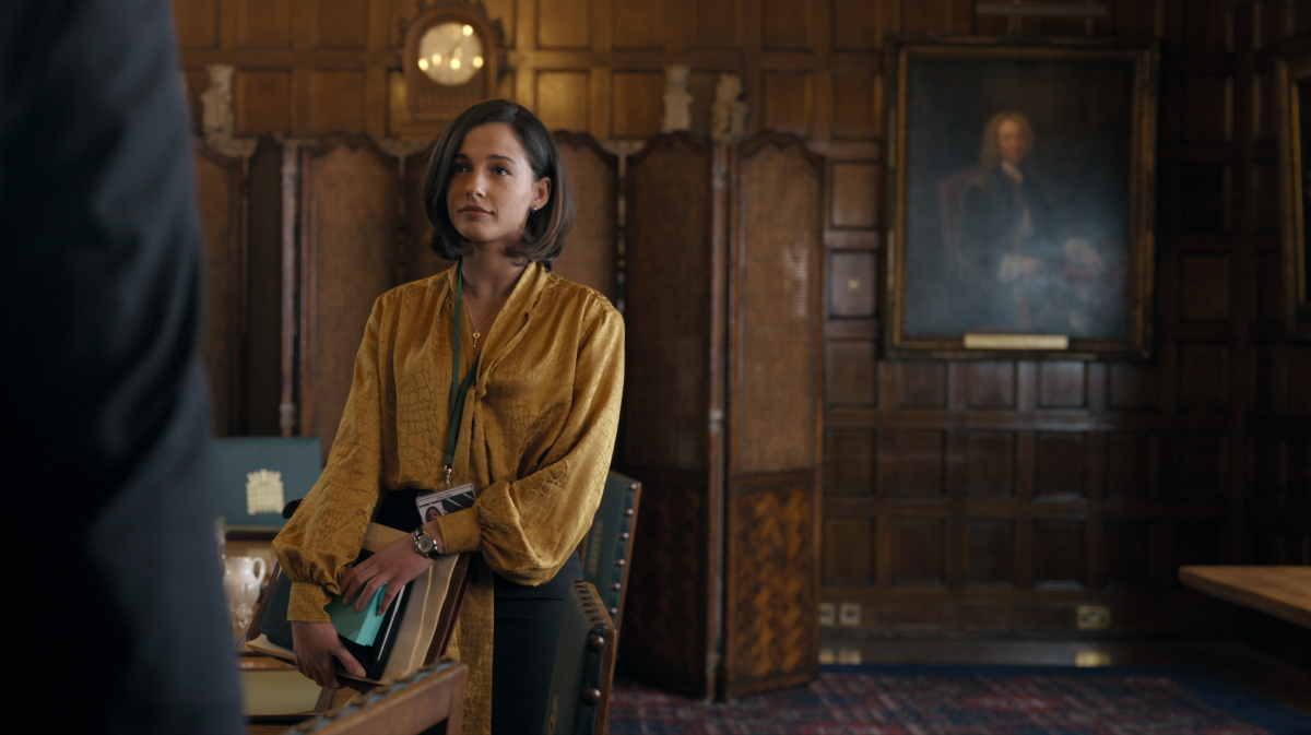 A woman in a yellow blouse with folders under her arm