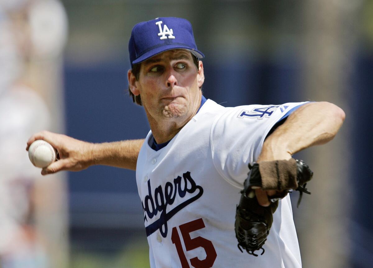 A man in a Dodgers uniform is pitching a baseball.