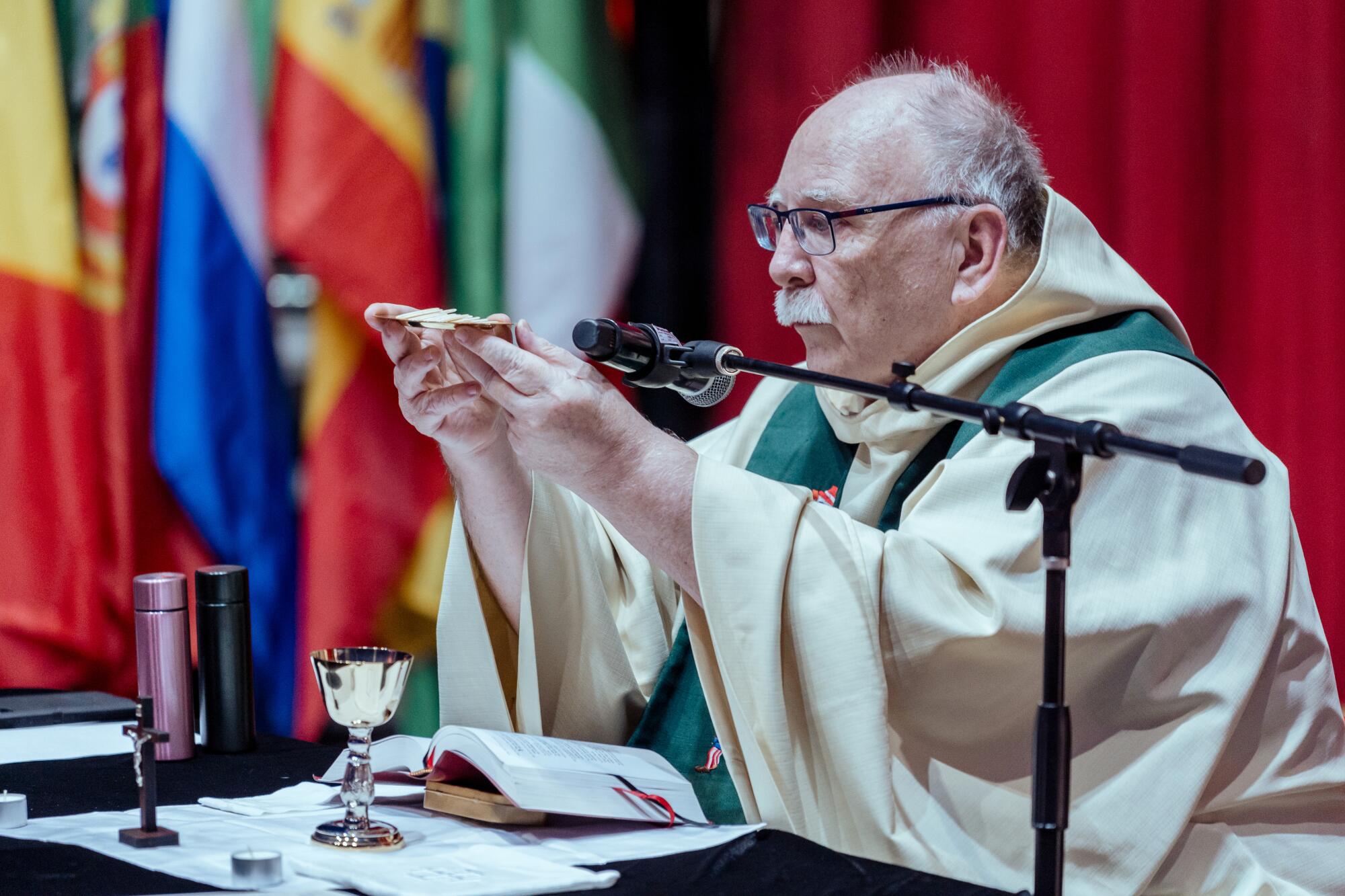 Father Frank Cancro during the Mass hold communion wafers in his hands.