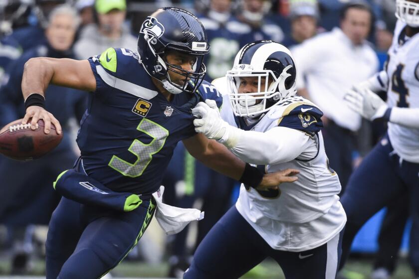 Seahawks Russell Wilson tries to keep Rams defensive tackle Aaron Donald at bay in the 2nd quarter.