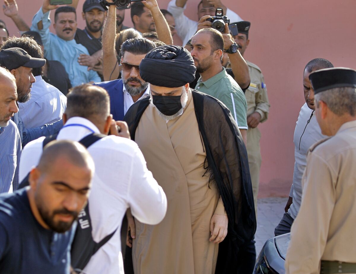 Populist Shiite cleric Muqtada al-Sadr arrives to a polling center along with several other men.