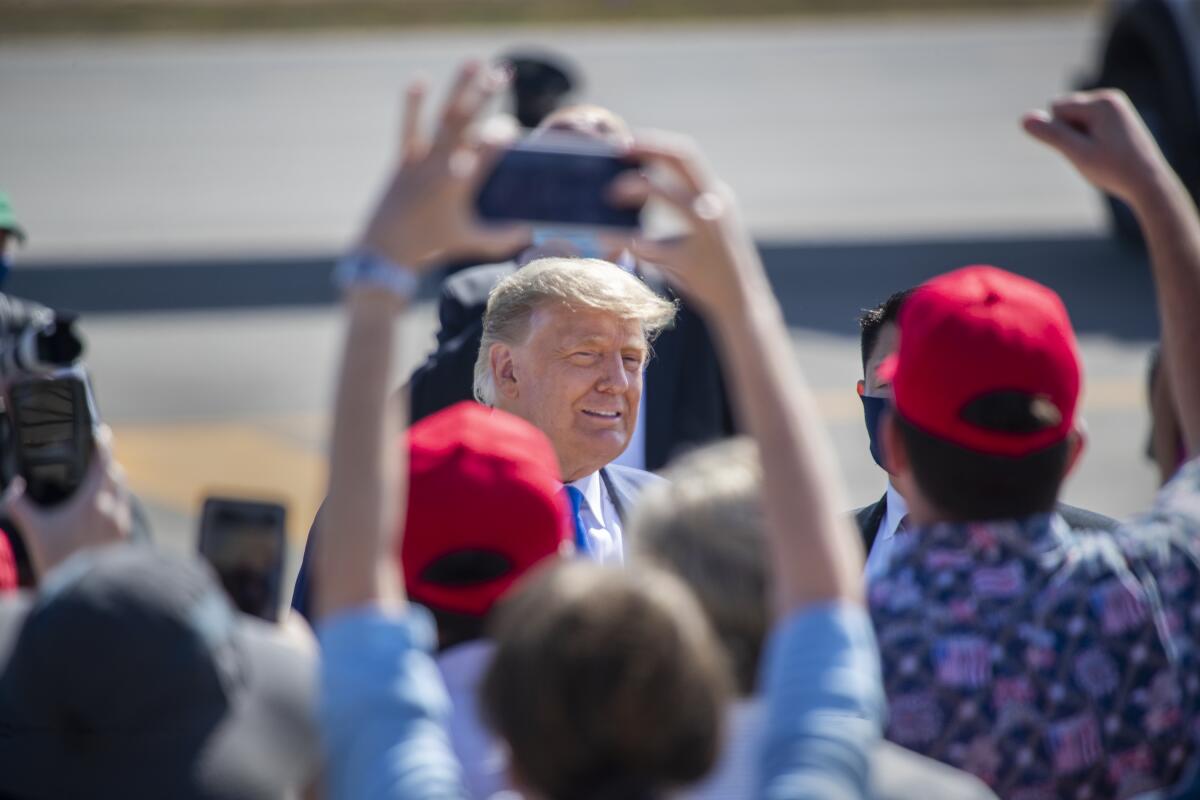 President Donald Trump greets supporters as he arrives on Air Force One at John Wayne Airport on Sunday.