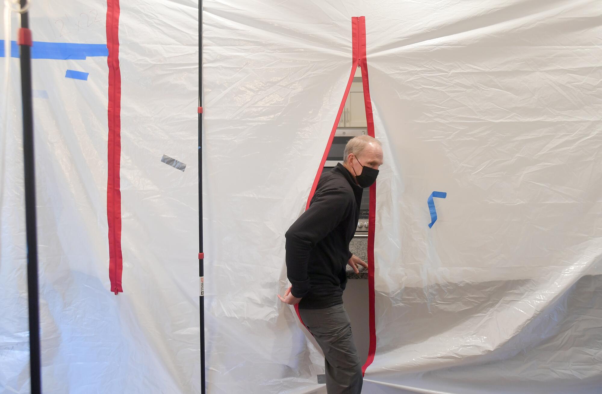 Rob Jackson steps out of a testing area protected by plastic sheeting.