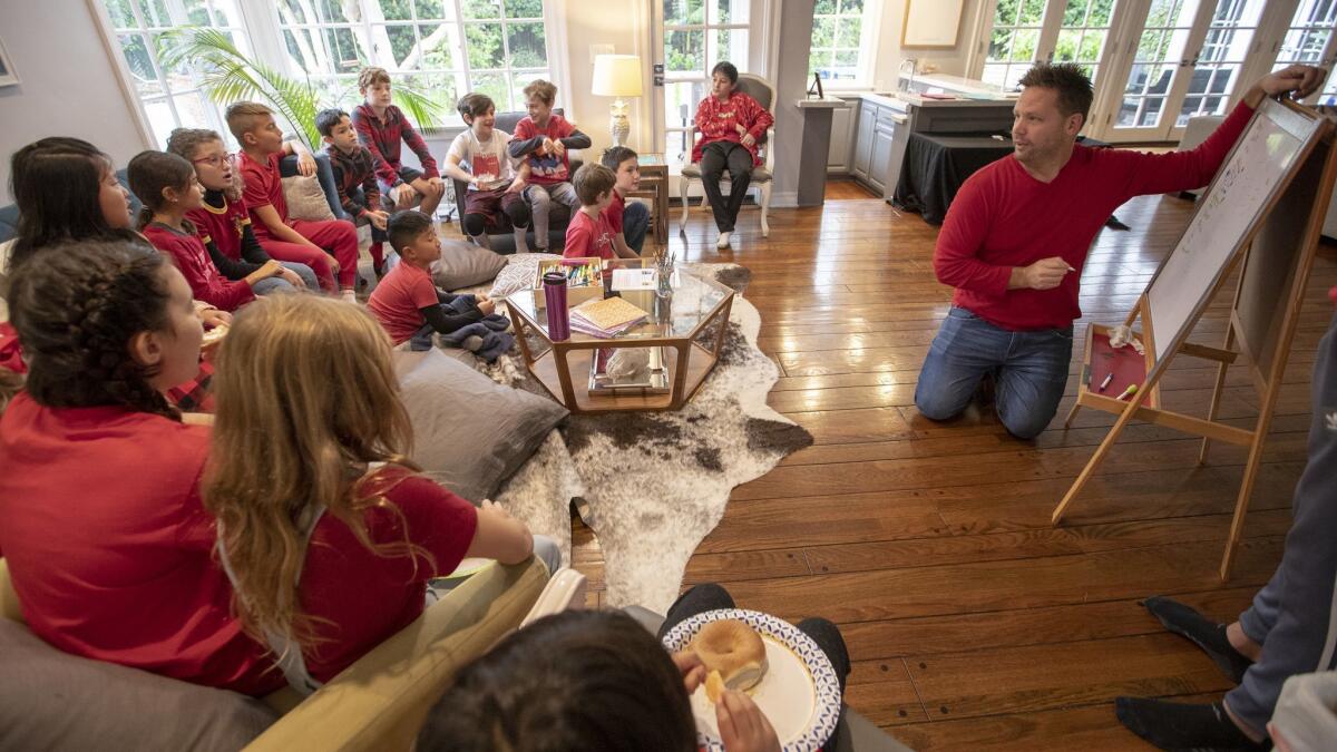 Corey Moss, right, draws on a dry-erase board during a math lesson for kids from Encino Charter Elementary School attending a community-organized "strike school" in his home in Encino. Parents are taking turns hosting kidsn in their homes ad creating a curriculum.