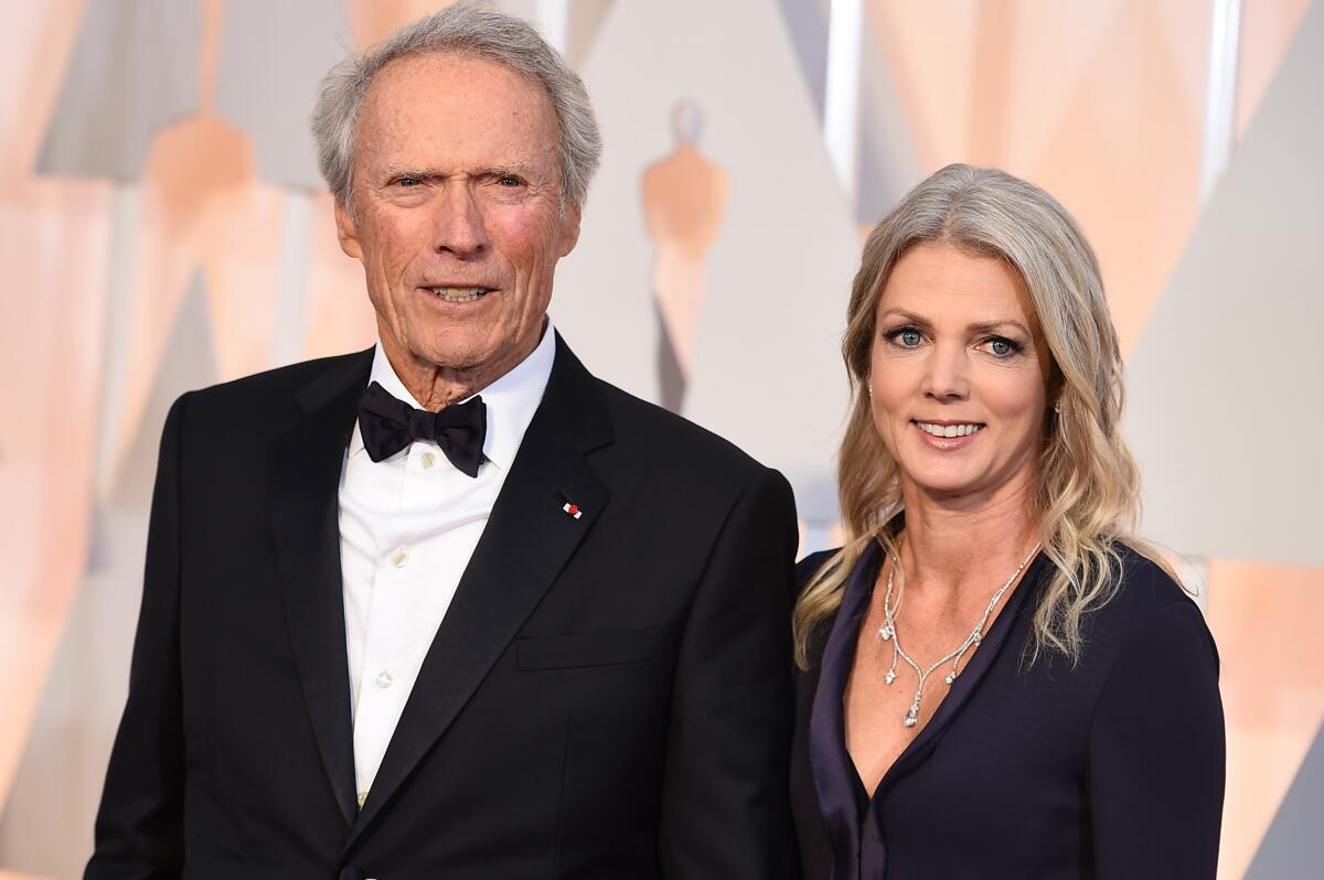 Clint Eastwood in a tuxedo and bow tie standing next to Christina Sandera in a dark gown