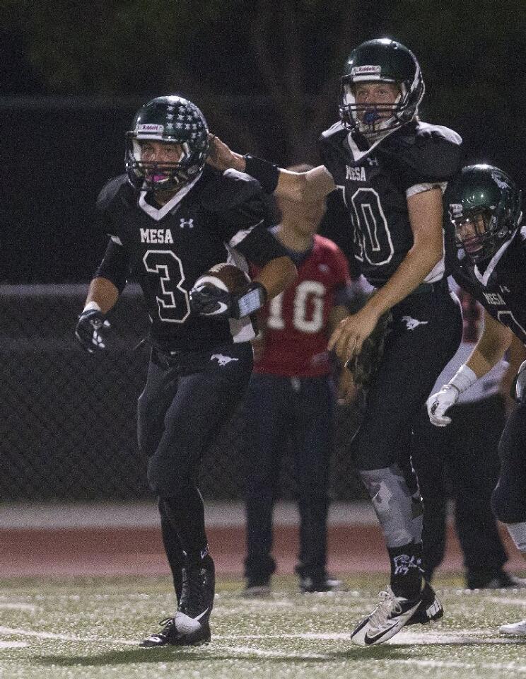 Costa Mesa High's Cameron Curet (3) is congratulated by quarterback Ben Swanson, right, after they connected on a touchdown pass during the first half against Katella in a nonleague game at Jim Scott Stadium on Thursday.