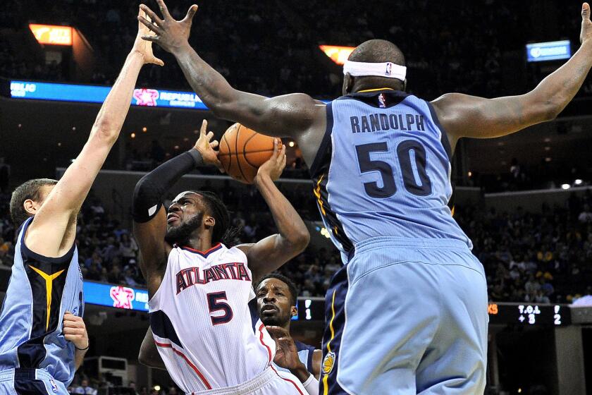 Hawks forward DeMarre Carroll (5) tries to score between Grizzlies center Marc Gasol, left, and forward Zach Randolph (50) in the second half Sunday.