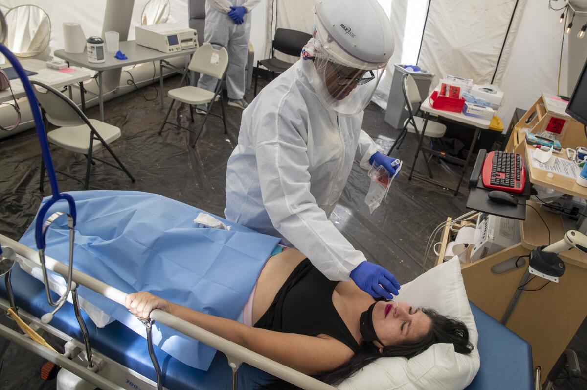 A woman in a hospital bed receives a nasal swab.