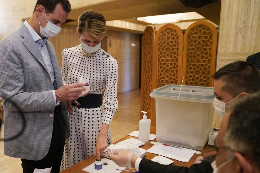 FILE - This file photo released July. 19, 2020 on the official Facebook page of Syrian Presidency, shows Syrian President Bashar Assad, left, and his wife Asma voting at a polling station in the parliamentary elections, in Damascus, Syria. The office of Syrian President Bashar Assad said Monday, March 8, 2021 that Assad and his wife have tested positive for the coronavirus and are both doing well. In a statement, Assad's office said the first couple did PCR tests after they felt minor symptoms consistent with the COVID-19 illness. (Syrian Presidency via AP, File)