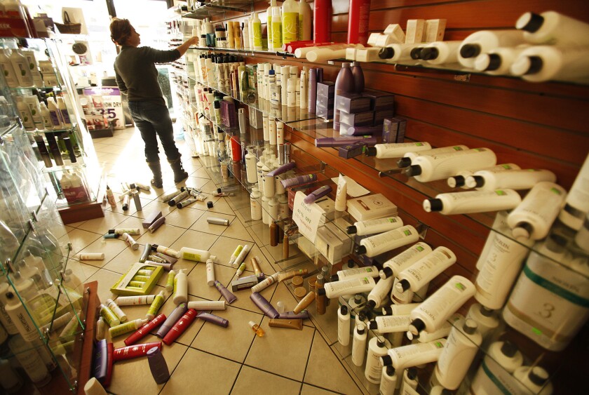 Roya Alagh, manager of Sherman Oaks Beauty Center, cleans up merchandise knocked from store shelves by a magnitude 4.4 earthquake that struck Los Angeles about 6:25 a.m. Monday.