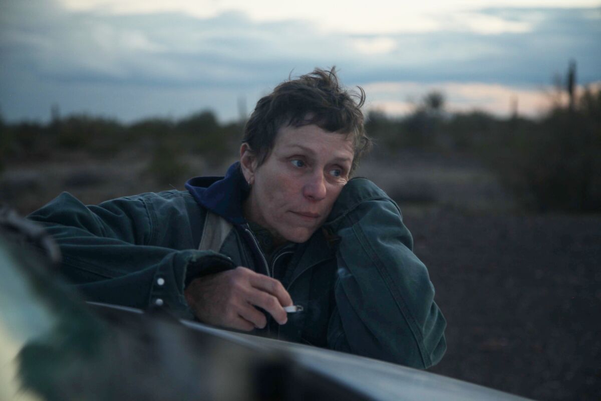 Frances McDormand resting on the hood of a car while holding a cigarette in "Nomadland."