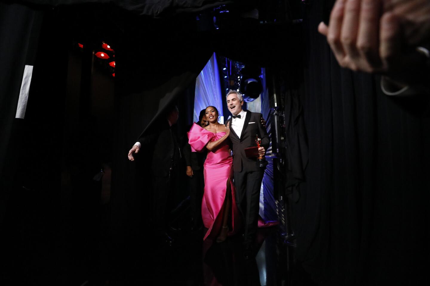 Alfonso Cuarón, after his win for foreign-language film, is accompanied offstage by presenter Angela Bassett.