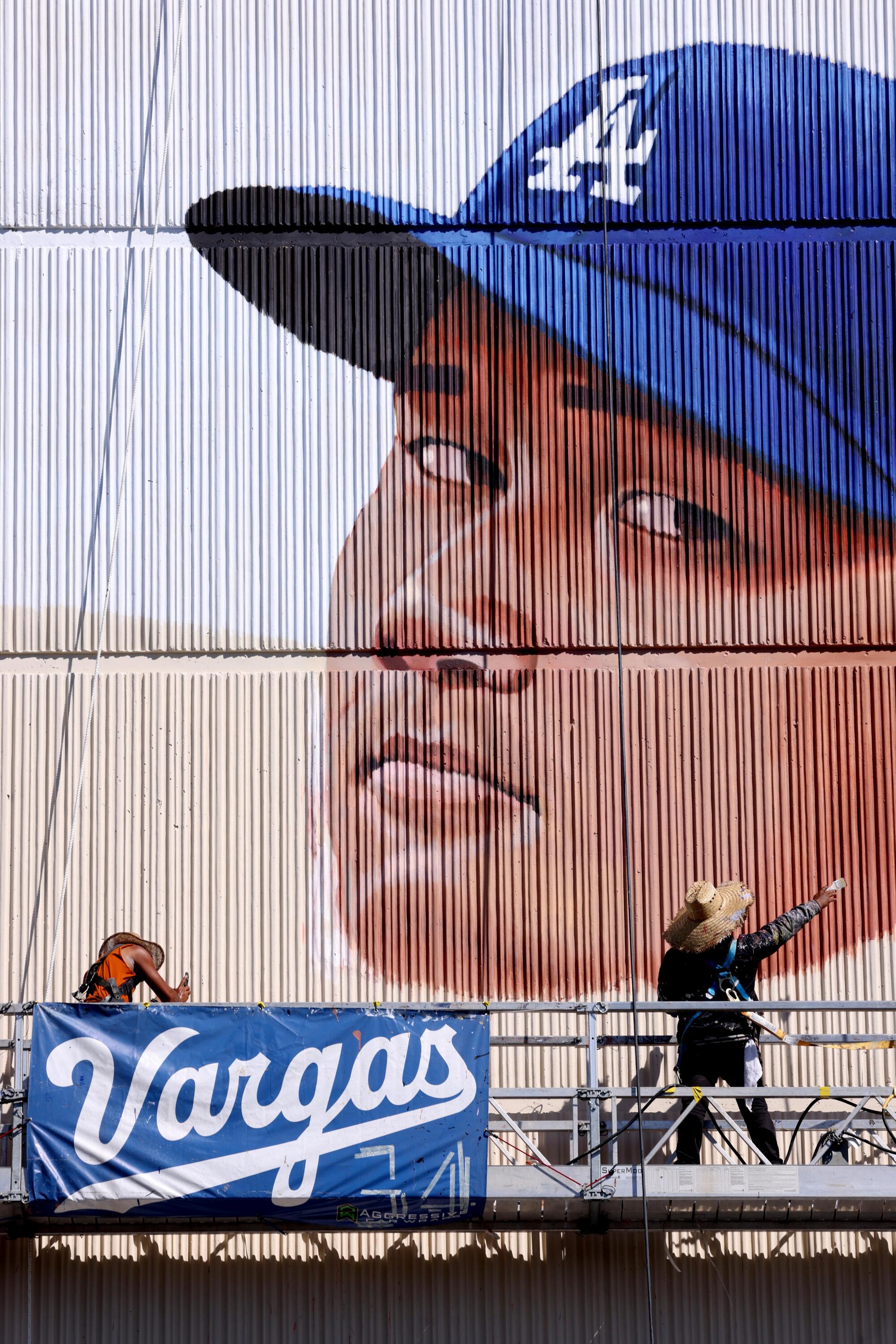 Bir yükselticinin üzerinde duran ve dokulu bir duvara devasa bir Shohei Ohtani yüzü çizen bir adam