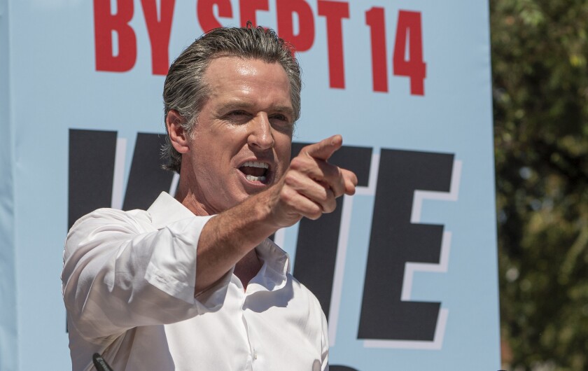 California Gov. Gavin Newsom stands in front of a sign reading "By Sept. 14: Vote."