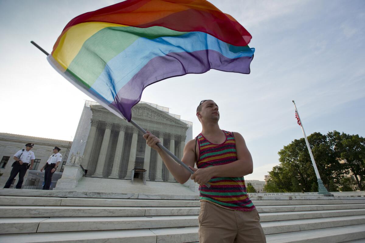 A gay rights advocate waves a rainbow flag in front of the Supreme Court in Washington in 2013. On Friday, a federal judge struck down two gay marriage bans in Alabama, a week after the Supreme Court agreed to hear same-sex marriage cases from four states.