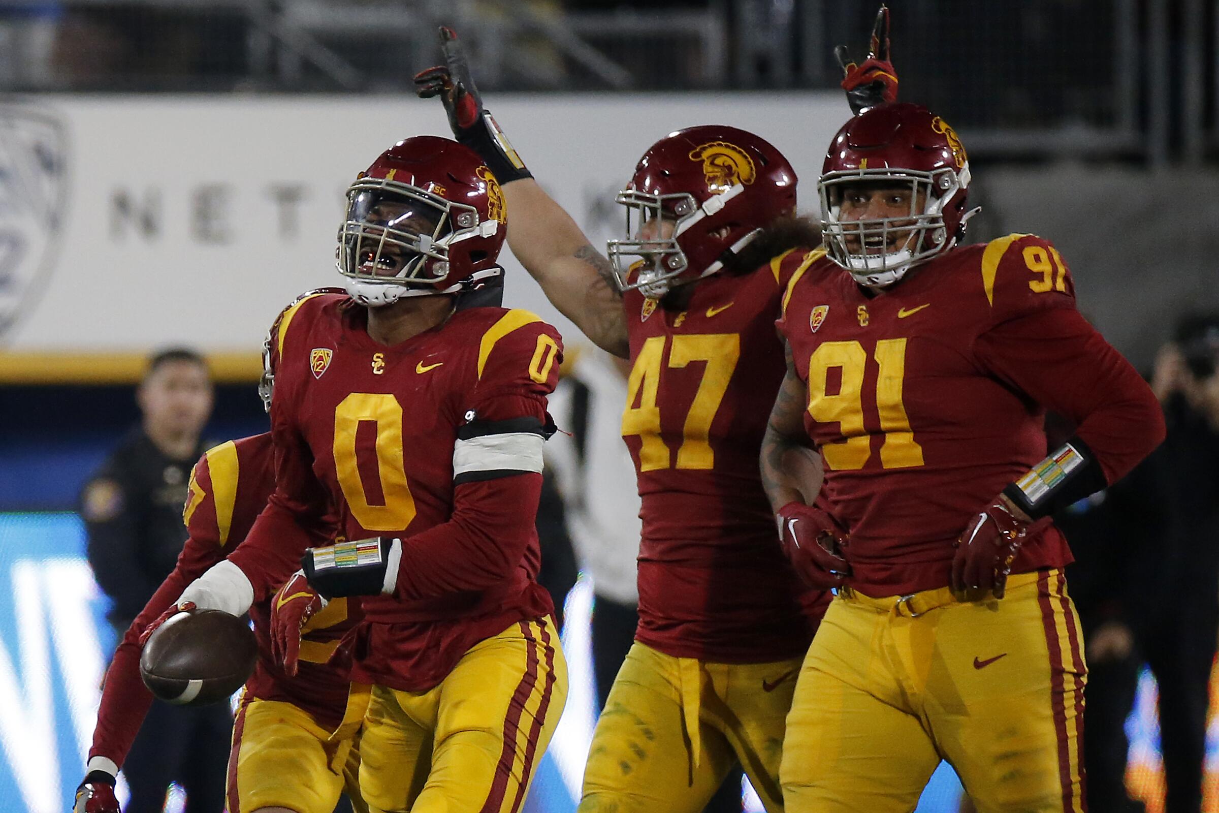 USC player raises his hands and his pointer fingers while teammates walk with him.