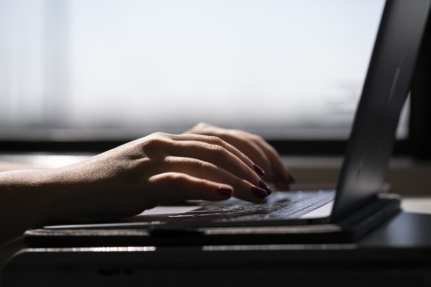 FILE - A woman types on a laptop on a train in New Jersey on May 18, 2021. When you’re trying to stay accountable and motivated while paying down debt, visual aids can offer encouragement and help you celebrate the small wins. (AP Photo/Jenny Kane)
