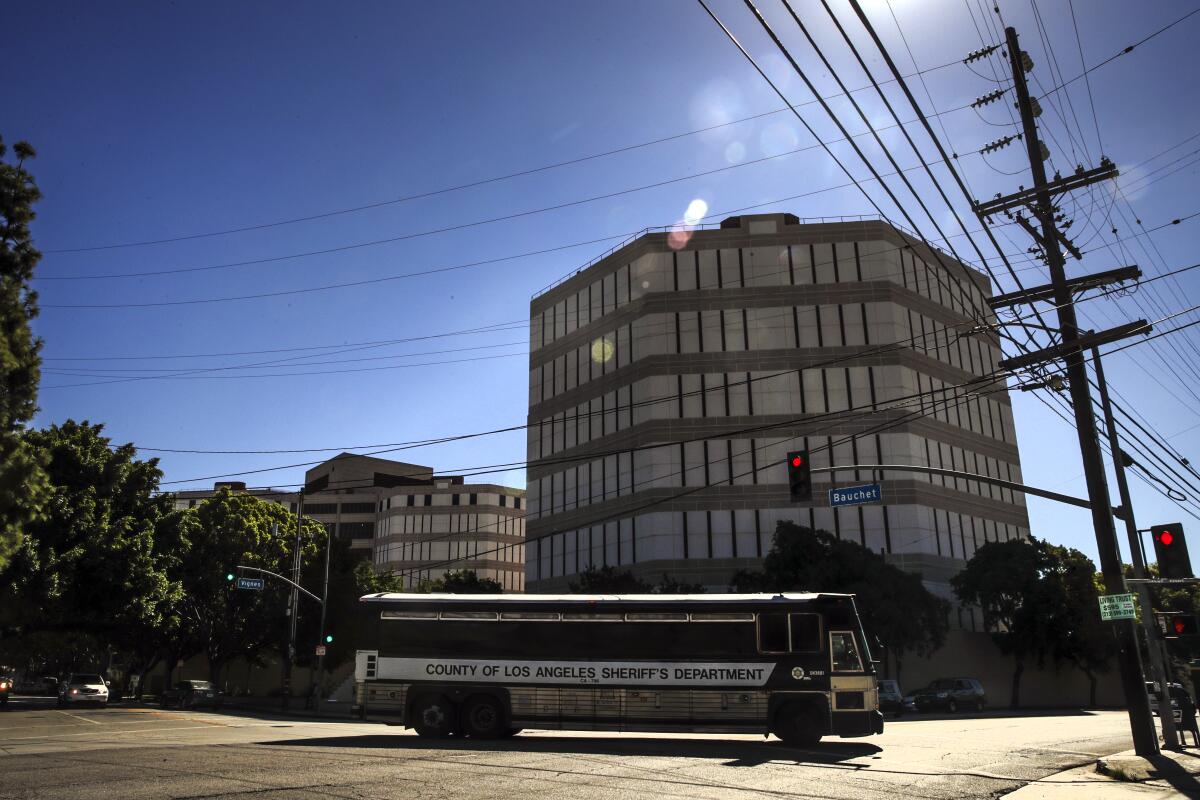 A multistory building rises behind a passing bus on a street corner.