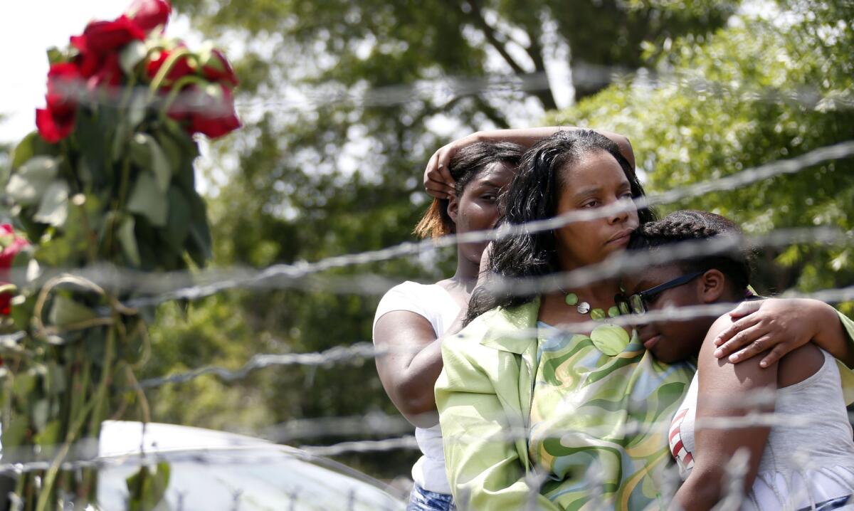 Area residents Waynetta Theodore, left, Alberta Harris and and Christiena Preston console one another on May 10 as they pay their respects at a makeshift memorial near the site where two police officers were killed in Hattiesburg, Miss.