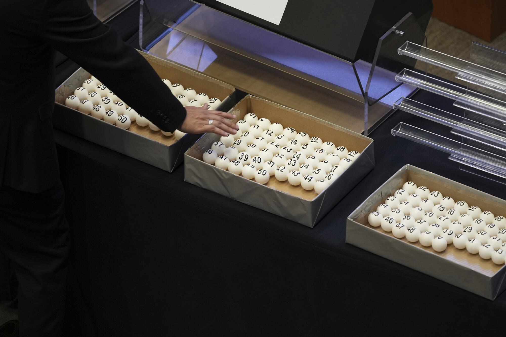 A person reaches toward balls with numbers printed on them