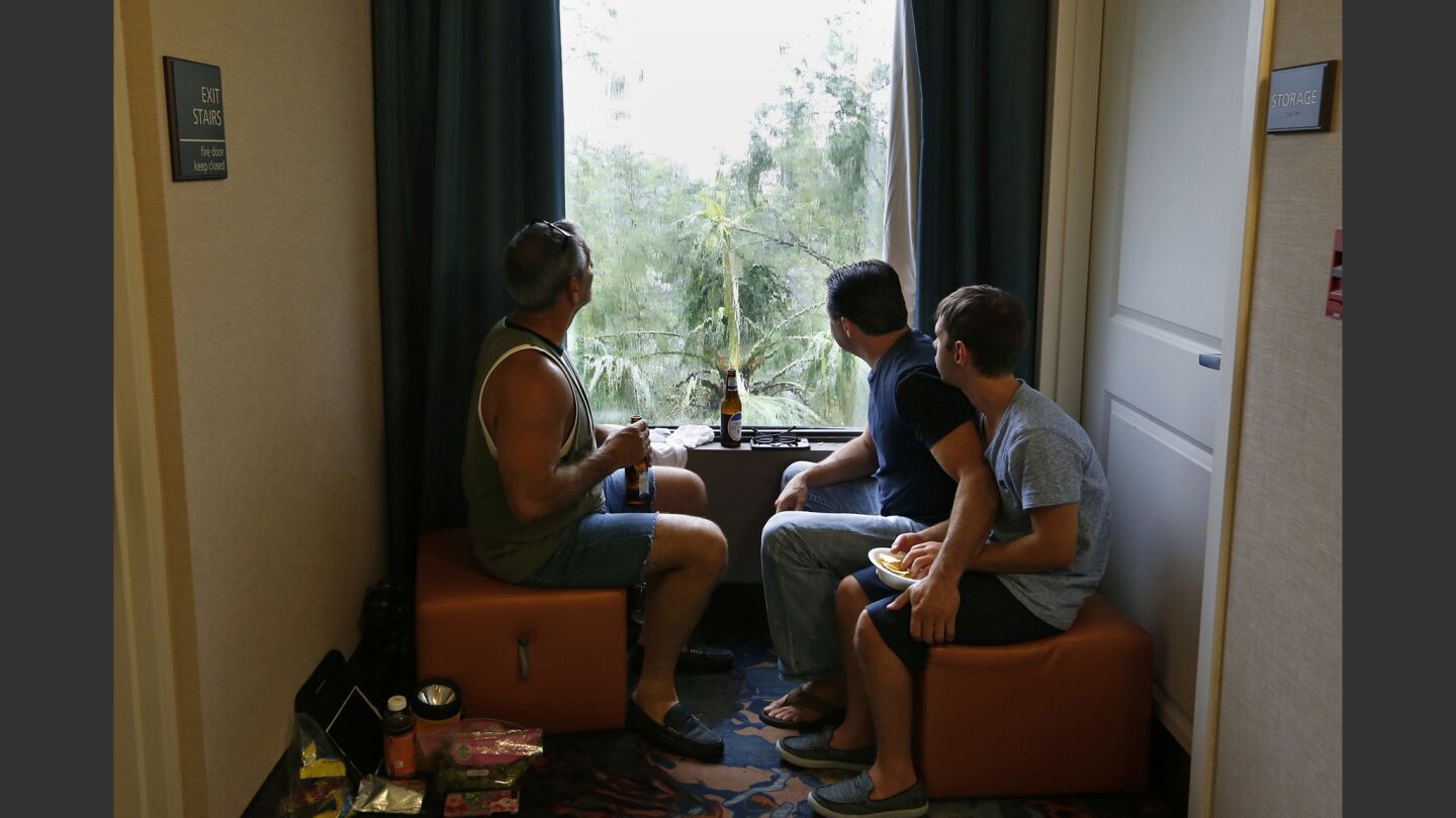 Jimmy Alfano, of Ft. Myers, holds onto Alec Hoskins who is autistic, while watching the storm gusts through the window of their Estero hotel with Frank Pairs.