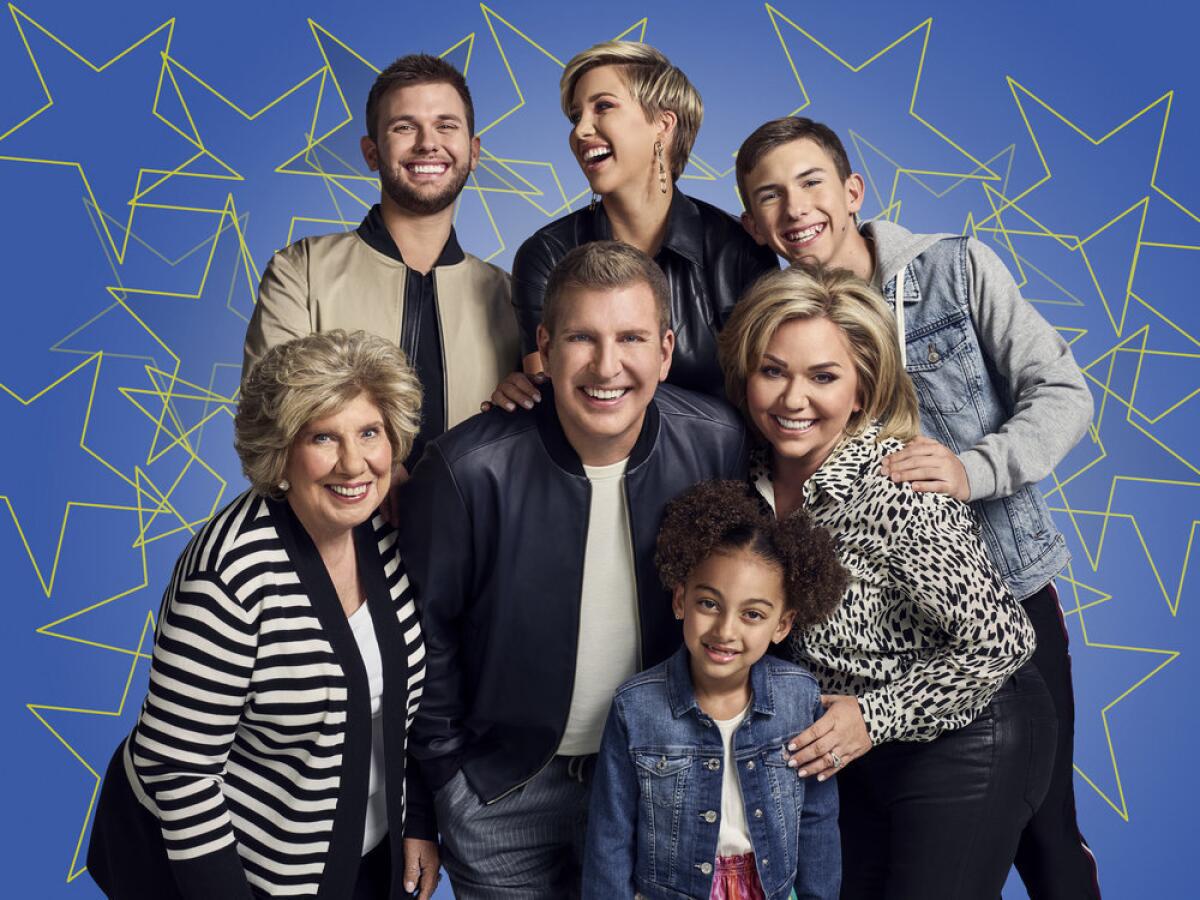 The Chrisley family in casual outfits posing in a group photo in front of a blue background with yellow stars