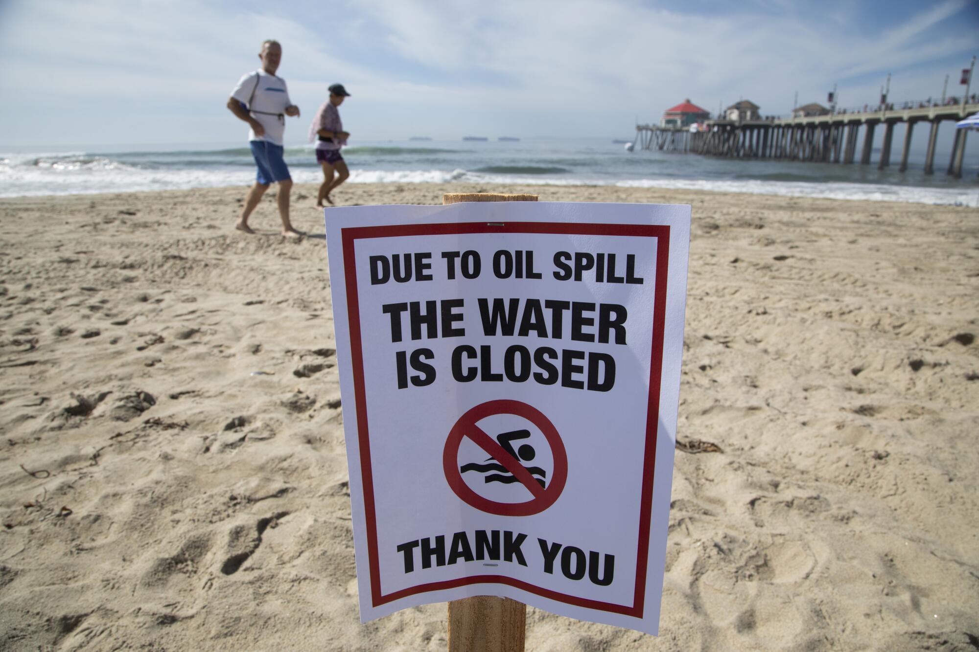 A sign warns visitors to stay out of the water because of the oil spill at the Huntington Beach Pier.