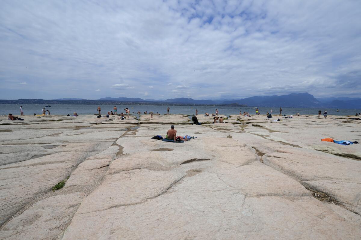Decenas de personas tomando sol en una parte reseca del Lago Garda de Italia 