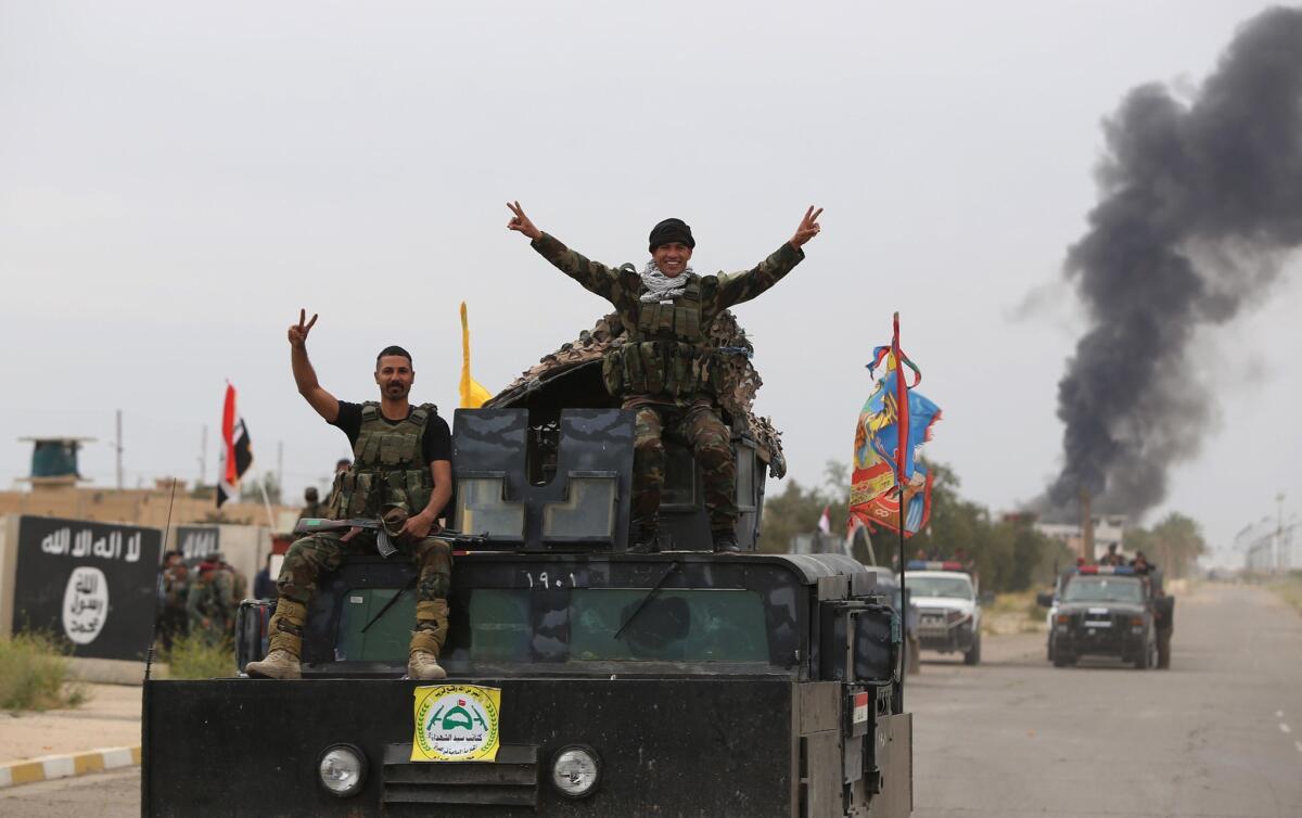 Iraqi security forces celebrate as they drive down a street in Tikrit on April 1.