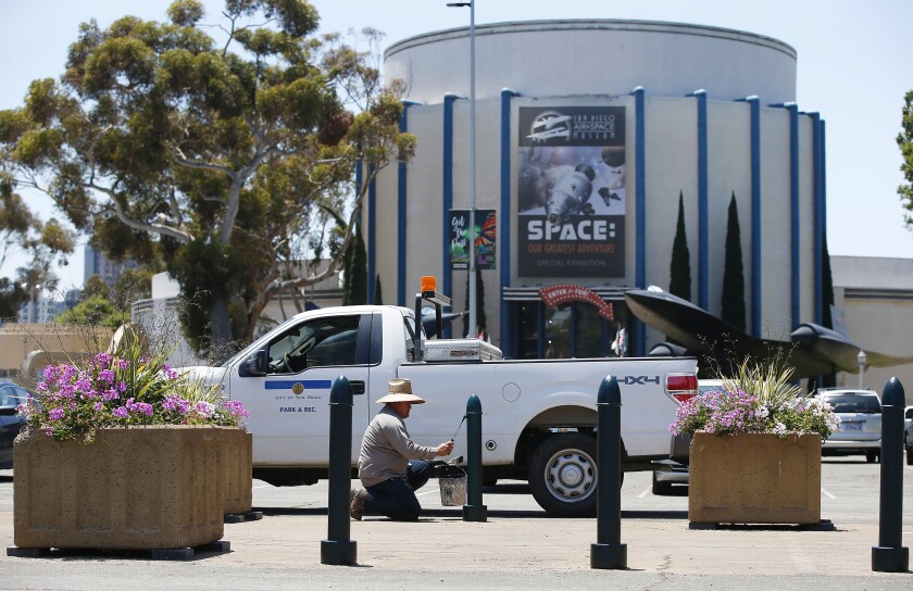 San Diego city worker Moises Torres paints posts in the parking lot of the San Diego Air and Space Museum on May 14, 2019. San Diego Mayor Kevin Faulconer directed the $9.3 million that had previously been allocated to the Plaza de Panama project go to a regional parks fund to ensure that those dollars go to other infrastructure priorities in Balboa Park. One of those priorities might be replacing the roof and painting the Air and Space Museum.